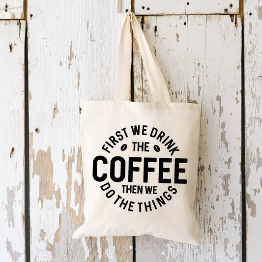 First We Drink the Coffee Tote Bag